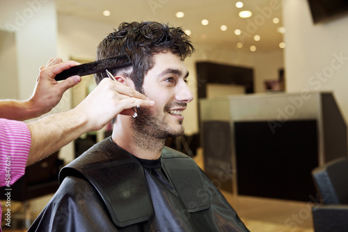 Photo: A male hairdresser cutting his male clients hair with scissors A male hairdresser cutting his male clients hair with scissors