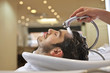 A male hairdresser rinsing a male clients hair