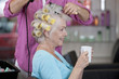 A senior woman having a hot drink whilst having her hair dried