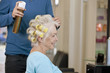 Male hairdresser applying hairspray to womans hair, close up