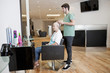 A male hairdresser applying product to his female clients hair