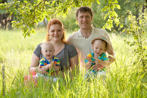 Photo: Big happy family, mother, father, children sitting on grass Big happy family, mother, father, children sitting on grass