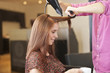 A male hairdresser blow drying a female clients hair