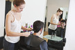 A female hairdresser cutting male clients hair with scissors