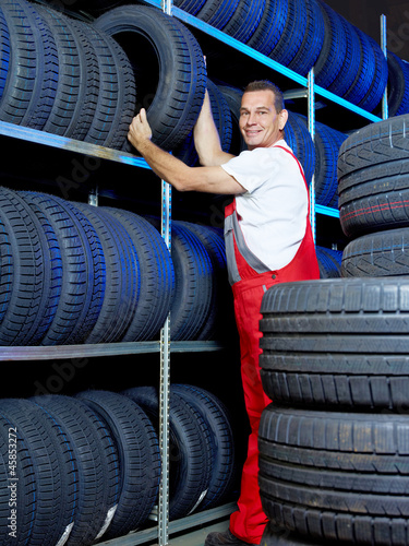 Photo: Car mechanic stores winter tire in a warehouse for tires Car mechanic stores winter tire in a warehouse for tires
