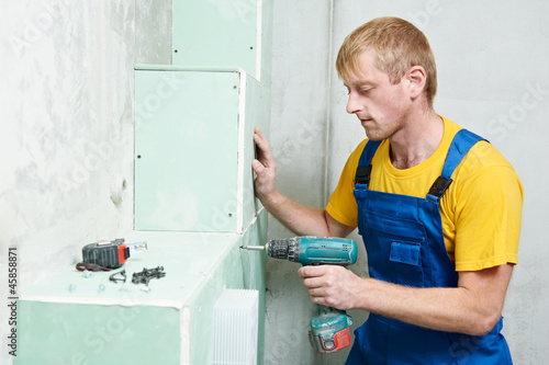 Photo: carpenter with plasterboard and screwdriver carpenter with plasterboard and screwdriver