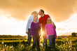 Happy family on meadow at sunset