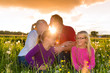 Happy family on meadow at sunset