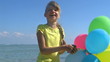 Child playing with balloons at the beach.
