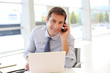 Portrait of businessman talking on mobile phone in office