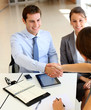 Business associates shaking hands in office