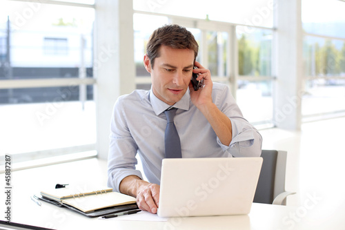 Photo: Portrait of businessman talking on mobile phone in office Portrait of businessman talking on mobile phone in office