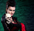 Halloween concept: young and sexy lady vampire holding a scull