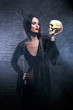 Halloween concept: young and sexy witch holding a human skull