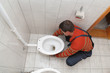 Photo: Plumber replacing broken toilet in a washroom Plumber replacing broken toilet in a washroom