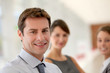 Portrait of businessman, team in background