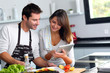 Couple in home kitchen using electronic tablet