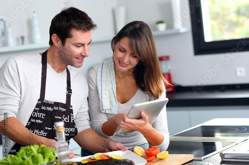 Photo: Couple in home kitchen using electronic tablet Couple in home kitchen using electronic tablet