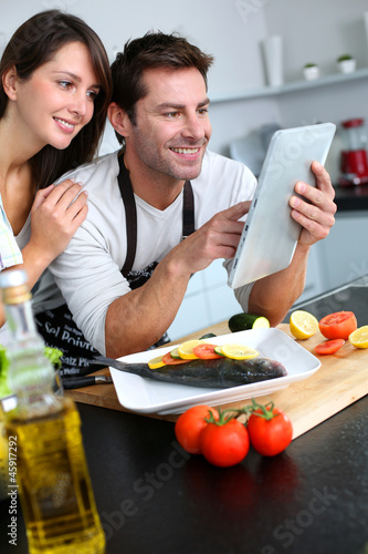 Photo: Couple in home kitchen using electronic tablet Couple in home kitchen using electronic tablet
