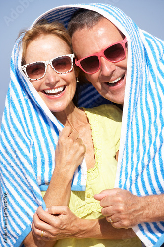 Photo: Senior Couple Sheltering From Sun On Beach Holiday Senior Couple Sheltering From Sun On Beach Holiday