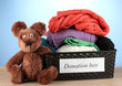 Donation box with clothing on blue background close-up