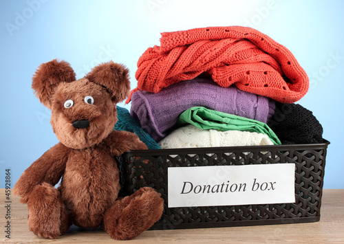 Photo: Donation box with clothing on blue background close-up Donation box with clothing on blue background close-up