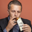 Man lighting his cigar with 100 dollars banknote
