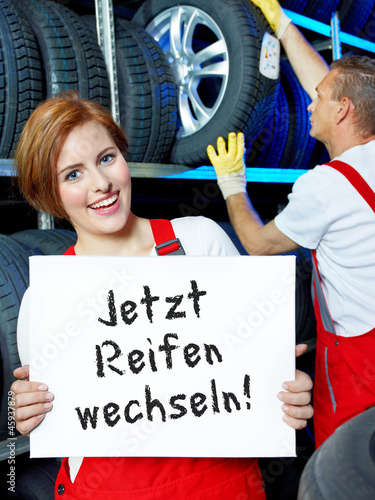 Photo: Female car mechanic is showing blackboard with tire changing Female car mechanic is showing blackboard with tire changing
