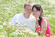 young couple seat in camomile field