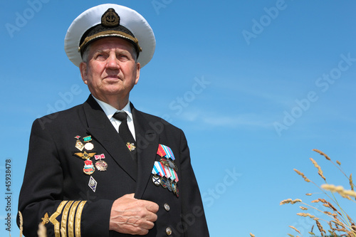 Photo: Grandfather in form, cap, ordens, medals pose background sky Grandfather in form, cap, ordens, medals pose background sky