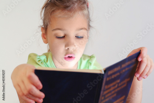 Photo: Little blue eyes girl with lighting on face read book Little blue eyes girl with lighting on face read book