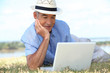 Foto: Senior man lying on the grass using a laptop computer Senior man lying on the grass using a laptop computer