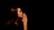 woman praying on a black background