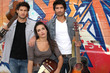 Three musician stood by graffiti