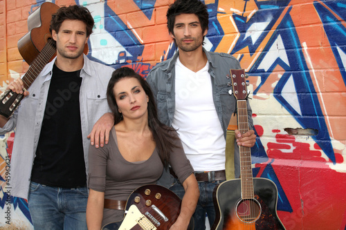 Photo: Three musician stood by graffiti Three musician stood by graffiti