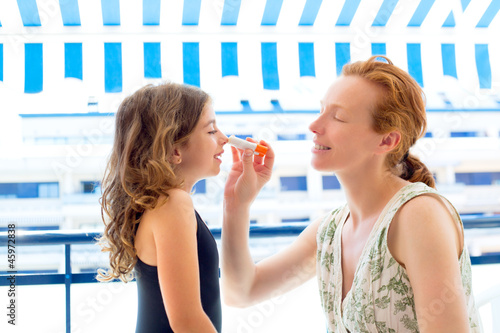 Photo: children girl with mother applying sunscreen children girl with mother applying sunscreen