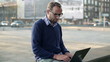 Young man with laptop in the city, steadicam shot