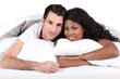 Man and woman smiling laid in a bed