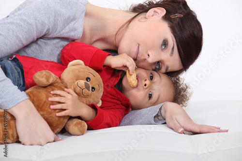 Photo: Mother and her adopted son laying on the bed. Mother and her adopted son laying on the bed.