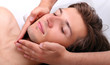 Handsome man enjoying face massage in spa salon