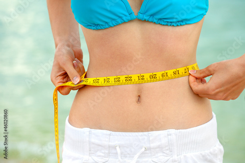 Photo: Young woman measuring waist Young woman measuring waist