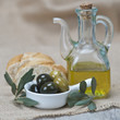 Aceite de oliva y aceitunas con pan sobre arpillera y madera