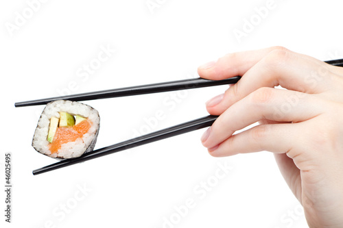 Photo: Hand holding fresh maki sushi roll with black chopsticks Hand holding fresh maki sushi roll with black chopsticks