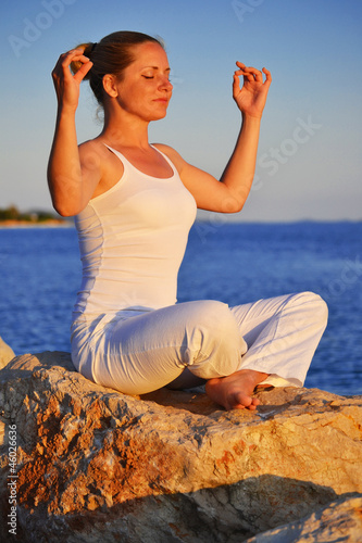 Photo: Young woman during yoga meditation on the beach Young woman during yoga meditation on the beach