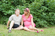 a happy young pregnant woman with her husband resting in a park
