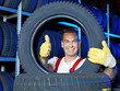 Funny car mechanic stores winter tires and shows thumb up