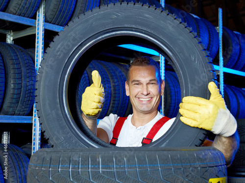 Photo: Funny car mechanic stores winter tires and shows thumb up Funny car mechanic stores winter tires and shows thumb up