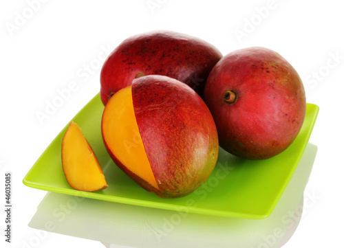 Photo: Ripe appetizing mango on green plate isolated on white Ripe appetizing mango on green plate isolated on white