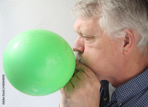 Photo: senior man blowing up balloon senior man blowing up balloon