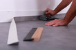 Man trimming linoleum against a skirting board